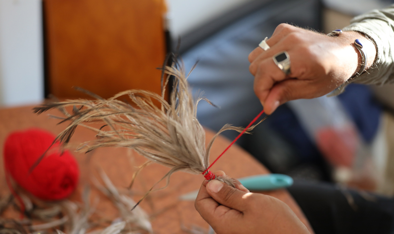 A man making an emu feather headdress.