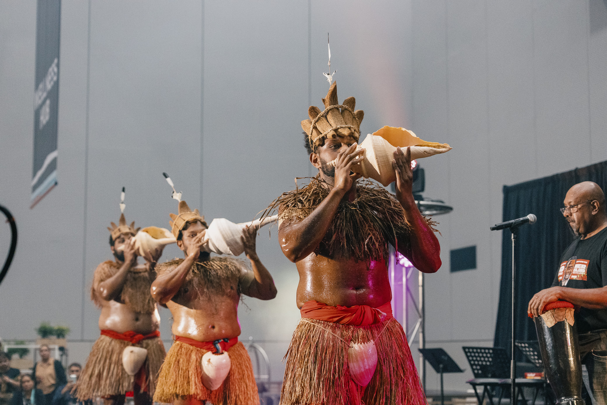 Torres Strait Islander men performing a traditional dance in a large venue